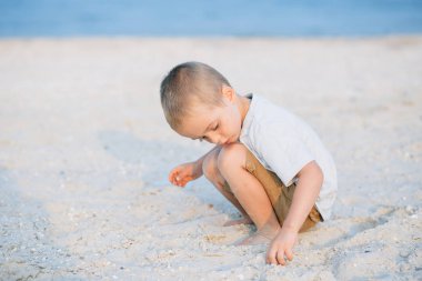 Portre ciddi küçük çocuk içinde belgili tanımlık kum deniz kenarında oynarken okyanus. Olumlu insan duyguları, duygular, joy. Vacations ayırdığınız ve yaz zevk komik şirin çocuk.