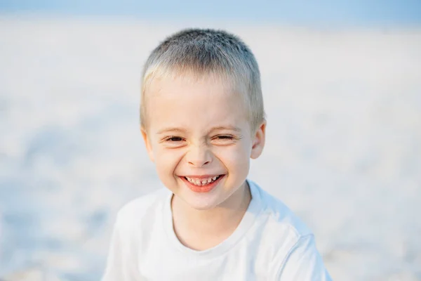 Adorable portrait of a happy boy, smiling at the camera in the sand near the sea, ocean. Positive human emotions, feelings, joy. Funny cute child taking vacations and enjoying summer.