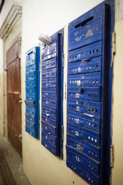 Posta kutularını harf ve broşürler dolu. Eski mavi posta kutuları apartmanın girişinde