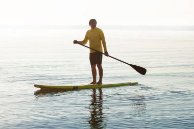 Gün batımı 12, yatılı atletik adam kürek silüeti sup