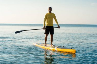 SUP silhouette of athletic man paddle boarding at sunset 15 clipart