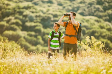 Baba ve oğul doğada yaz aylarında hiking. Onlar are istimal dürbün.