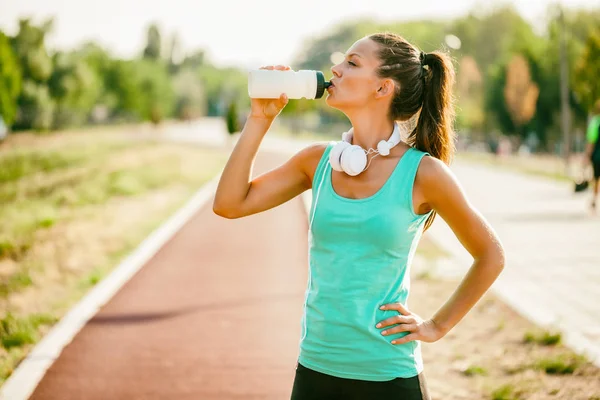 若い女性は 晴れた日にジョギングの後の飲料水をします — ストック写真
