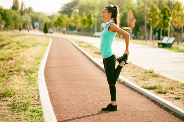 Genç kadın güneşli günde egzersiz olduğunu. O vücudu germe.