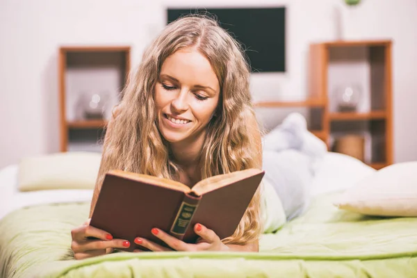Νεαρή Γυναίκα Ξαπλωμένη Στο Κρεβάτι Και Την Ανάγνωση Του Βιβλίου — Φωτογραφία Αρχείου