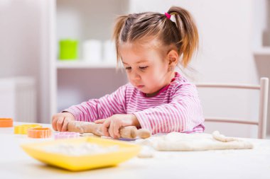 Küçük kız oynamaya ve mutfakta kurabiye yapma. 
