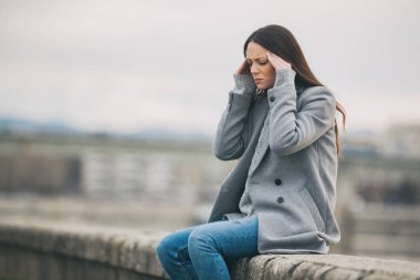 Yorgun kadın işten sonra baş ağrısı geçiriyor. 