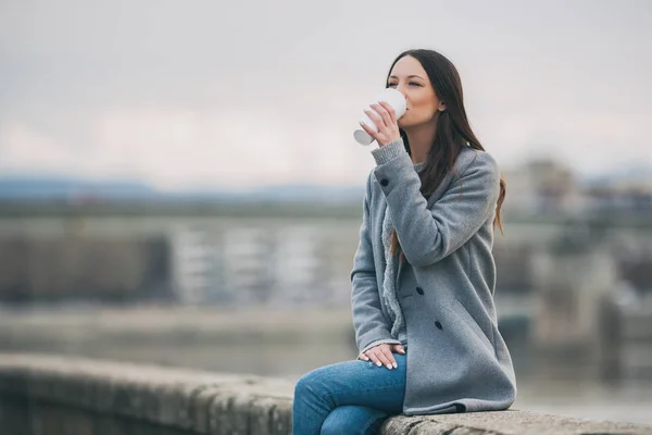 Young woman is drinking coffee to go after work.