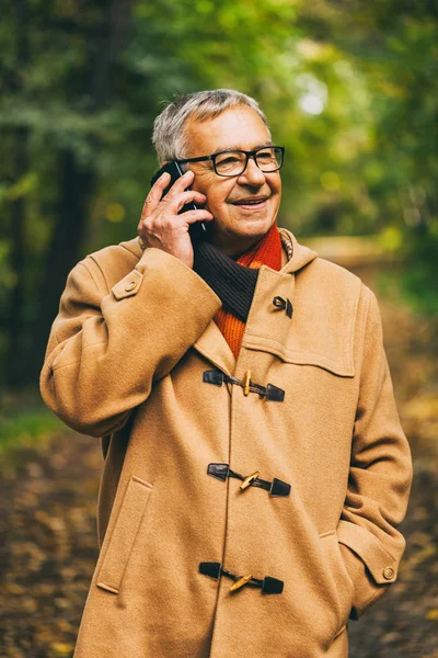 快乐的老人在公园里谈论秋天的电话 — 图库照片