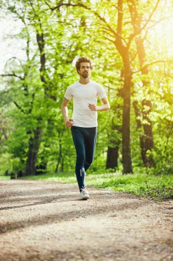 Genç adam parkta koşu. 