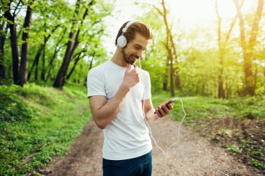 Genç adam parkta koşu için hazırlanıyor. 