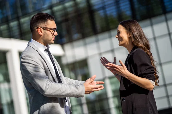 Business colleagues are talking outside the company building.