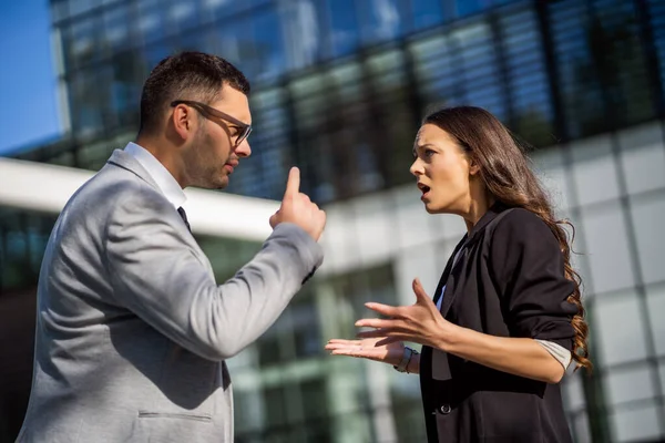 Business colleagues are arguing outside the company building.