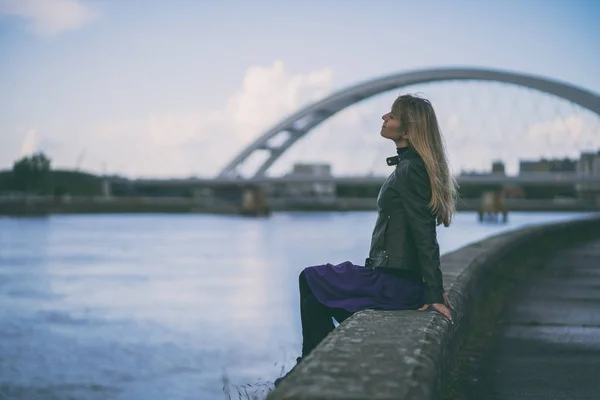 Adult woman relaxing at river bank in the city.