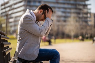 Genç işadamı kovulduktan sonra parkta oturuyor. Depresyona girmiş..