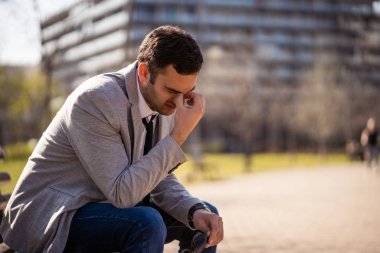 Genç işadamı kovulduktan sonra parkta oturuyor. Depresyona girmiş..