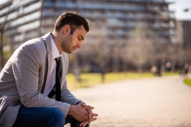 Genç yorgun işadamı parkta işten sonra dinleniyor.