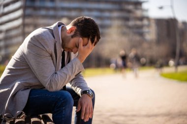 Genç işadamı kovulduktan sonra parkta oturuyor. Depresyona girmiş..