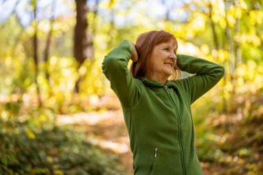 Kıdemli kadın güneşli bir günde parkta egzersiz yapıyor..