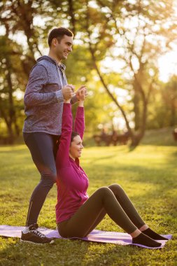 Fizyoterapist genç hastaya siyatik kurtarma için egzersizler gösteriyor.