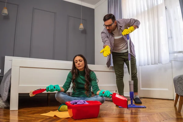 Woman is lazy. Man is telling her to continue cleaning their apartment.