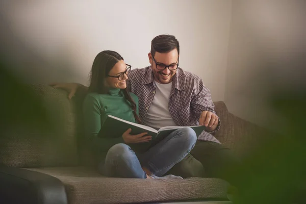 Glückliches Paar Sitzt Hause Auf Sofa Und Schaut Auf Buch — Stockfoto