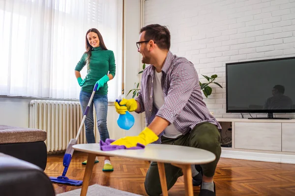 Young happy couple is cleaning their apartment.