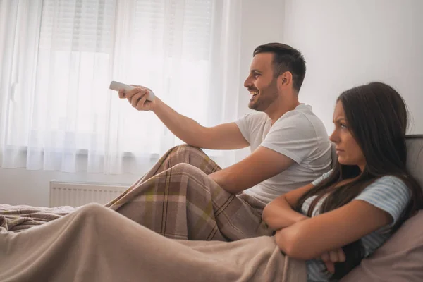 若い夫婦は寝室でテレビを見ている 女は怒ってる — ストック写真