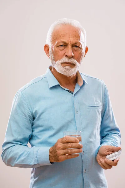 拿着药和水的严肃老人的画像 — 图库照片