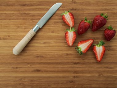Tahta arka planda taze çilek ve bıçak.