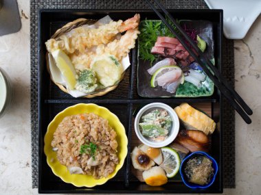 Japon Bento kutusu, çiğ balık, pirinç, tempura ve sebzelerle dolu.