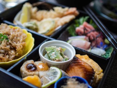 Japon Bento kutusu, çiğ balık, pirinç, tempura ve sebzelerle dolu.