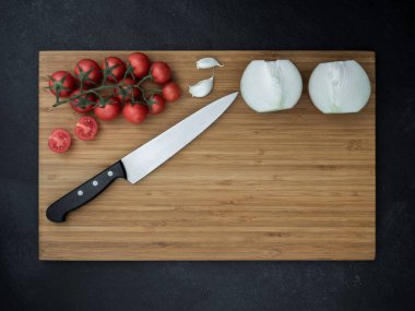 Çeri domates, soğan, sarımsak ve mutfak bıçağı. en üstteki görünüm