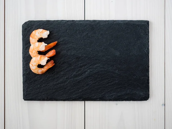 cooked peeled shrimps on slate board. top view