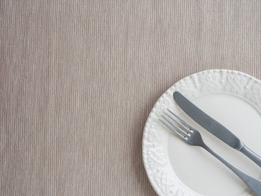 Tabak ve klasik çatal bıçak seti bej kaplamalı. Masa takımı. en üstteki görünüm