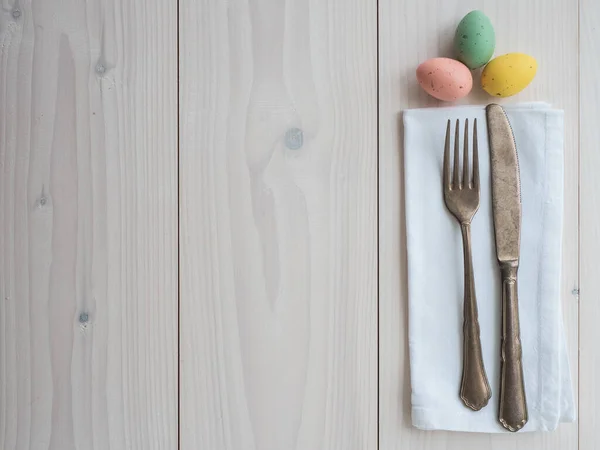 Paskalya yumurtaları, eski çatal bıçak takımı ve tahta üzerinde peçete. tablo üst görünümü ayarla
