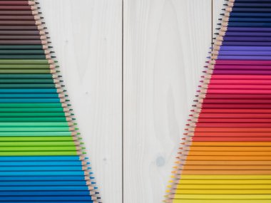 Ahşap arka planda iki sıra renkli kalem. en üstteki görünüm
