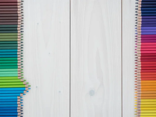 Ahşap arka planda iki sıra renkli kalem. en üstteki görünüm