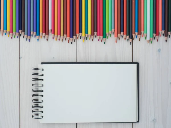 Conjunto Lápices Colores Dispuestos Una Fila Cuaderno Sobre Fondo Madera — Foto de Stock