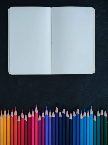 Fila Lápices Colores Cuaderno Sobre Fondo Pizarra Vista Superior — Foto de Stock