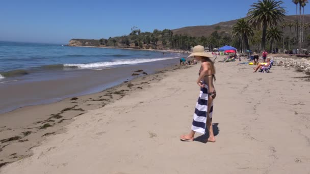一个戴着草帽的女人躺在加利福尼亚海滩上晒太阳 — 图库视频影像