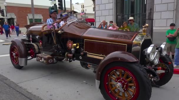 人々は ディスプレイ上の古典的な車を見て小さな町の通りをさまよう — ストック動画