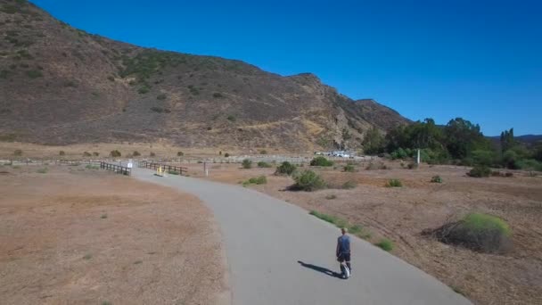 カリフォルニアの道路を電動自転車に乗っている男の後の空中映像 — ストック動画