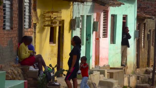 キューバの人々はトリニダードを通ってメインストリートに並ぶカラフルな建物の横にぶら下がっています キューバ — ストック動画