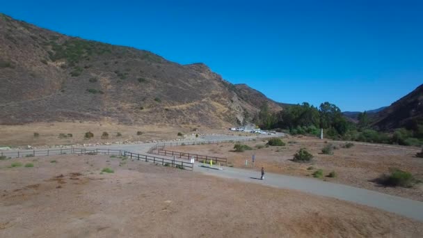 カリフォルニアの道路を電動自転車に乗っている男の後の空中映像 — ストック動画