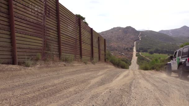 国境警備隊の車両がカリフォルニア砂漠のメキシコ国境防壁フェンスに沿って移動します — ストック動画