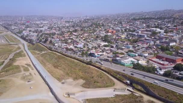 メキシコとサンディエゴをティフアナから隔てる国境の壁のフェンスの上の高い空中 — ストック動画