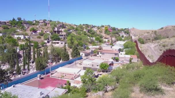 航空ショットはノガレスの町の近くにメキシコ国境の壁のフェンスを渡って移動します — ストック動画