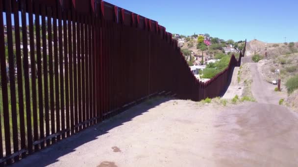 メキシコの国境の壁のフェンスに沿ってゆっくりと上昇する空中はノガレスの町を明らかにする — ストック動画