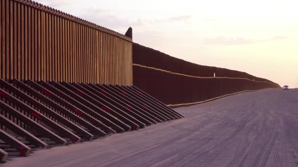 チリは カリフォルニア州のインペリアルサンド砂丘近くの米国メキシコ国境の国境の壁で日没時に吹きます — ストック動画
